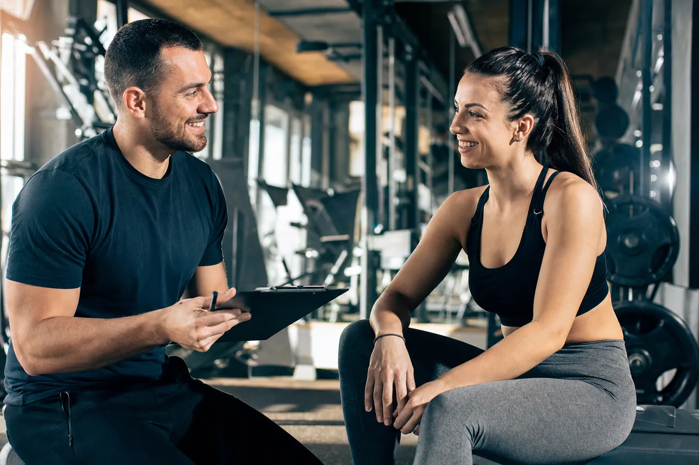 Entrenador motivando a un miembro feliz en un gimnasio moderno